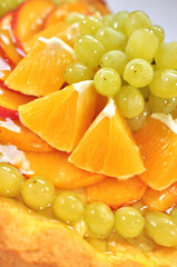 Tasty fruit cake with jelly close up, grapes, oranges, peach, vertical fruit background