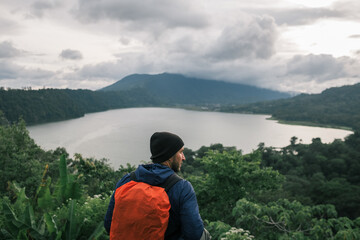 Fototapeta na wymiar A man traveler with backpack admires the mountain landscape.