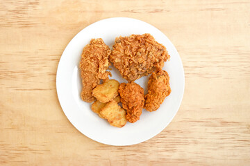Delicious crispy fried chicken in white plate on wood background