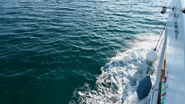 Wake of cruise ship on blue sea. Speed boat on blue ocean splashing water and breaking the waves. Ferry boat cruising. 