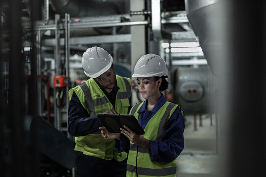 Male engineer and female engineer working together in an industrial plant room
