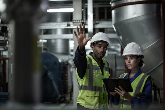 Male engineer training a female engineer in an industrial plant room