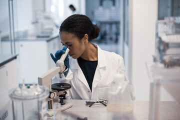 African american female scientist looking at microscope