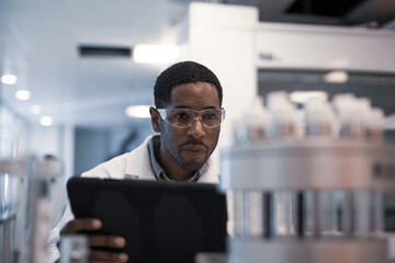 African American male scientist recording data on a digital tablet in a laboratory