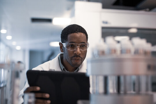 African American male scientist recording data on a digital tablet in a laboratory