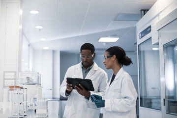 Scientists discussing results of experiment using digital tablet