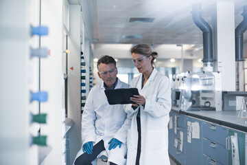 Scientists looking at results of experiment on a digital tablet