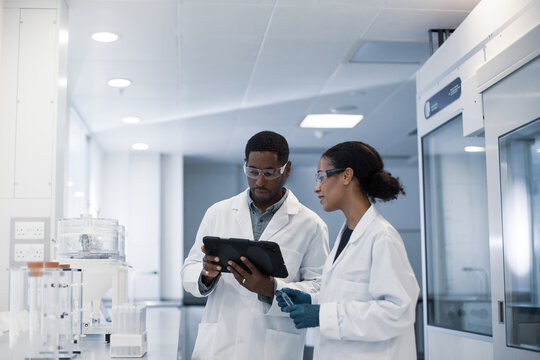 Scientists discussing results of experiment using digital tablet
