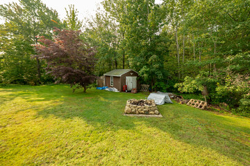 backyard tool shed and a pit on the outside of a yard. Many trees are surrounding the shed.