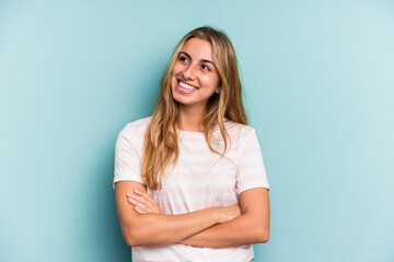 Fototapeta premium Young caucasian blonde woman isolated on blue background smiling confident with crossed arms.
