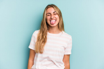 Obraz premium Young caucasian blonde woman isolated on blue background funny and friendly sticking out tongue.