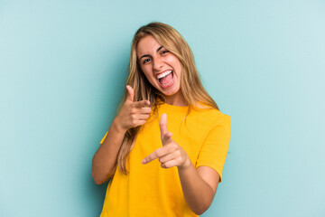 Young caucasian blonde woman isolated on blue background  pointing to front with fingers.