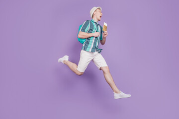 Fototapeta na wymiar Profile portrait of crazy tourist guy jump run hold tickets visa on violet background