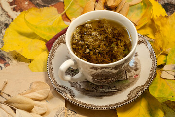 Cozy autumn day at home - English porcelain cup of hot herbal tea, colorful autumn leaves and old letters
