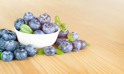 fresh blueberries in a plate on a wooden table, front view