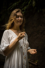 Caucasian woman keeping count during pray and meditation. Buddhist japa mala. Strands of gemstones beads. Religion concept. Hand in gyan mudra. Woman wearing dress. Bali, Indonesia