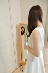 鏡に映る白いドレスを着た若くスリムな女性	