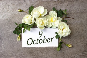 October 9th. Day 9 of month, Calendar date. White roses border on pastel grey background with...