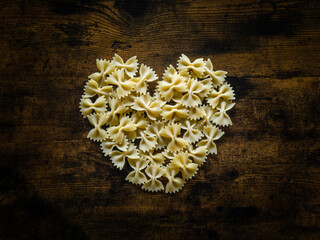 Fototapeta Des pâtes Farfalle crues sur une table en bois en forme de coeur obraz