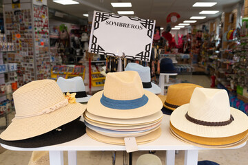 Straw hats displayed in front of a traditional shop in Cordoba, Spain. The text 