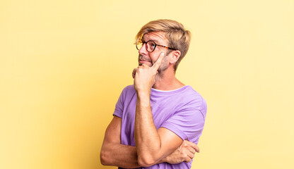 handsome blond adult man with a concentrated look, wondering with a doubtful expression, looking up...