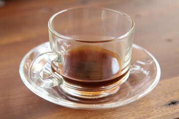 Hot coffee in a clear glass cup after drinking on wooden table.