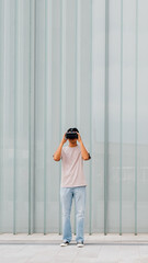 Young asian man outdoor experiencing virtual reality using 3D goggles - advertising copyspace banner
