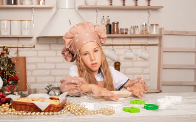 little girl in the background of the kitchen at home sculpts dough cook charming with a place for dough
