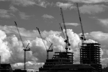Silhouettes of cranes and buildings under construction in downtown London set against a dramatic...