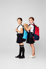 two happy little cheerful friends schoolgirls with backpacks