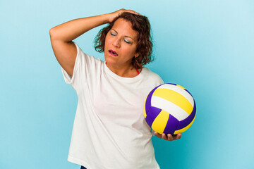 Middle age latin woman playing volleyball isolated on blue background being shocked, she has remembered important meeting.