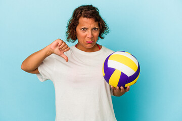 Middle age latin woman playing volleyball isolated on blue background showing a dislike gesture, thumbs down. Disagreement concept.