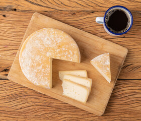 Artisanal Canastra cheese from Minas Gerais, Brazil with coffee cup over wooden table