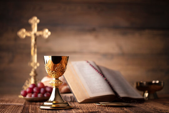Catholic religion concept. Catholic symbols composition. The Cross, Holy Bible, rosary and golden chalice on the altar.
