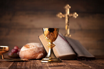 Catholic religion concept. Catholic symbols composition. The Cross, Holy Bible, rosary and golden chalice on the altar.