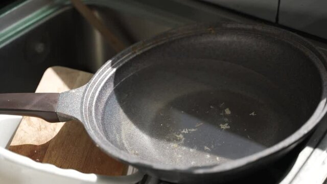 Unwashed dirty Teflon pan and appliances at the kitchen sink with leaking water drop