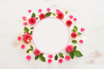 White wooden delicate background with pink roses and petals. Top view