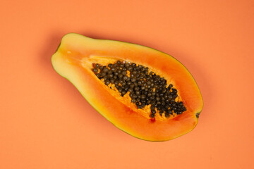 Papaya fruit on a orange background. Half papaya.