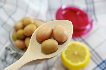 green pickled olives in a wooden spoon