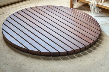 Round table top made of wooden slats for outdoor table lying on dusty floor in workshop close view