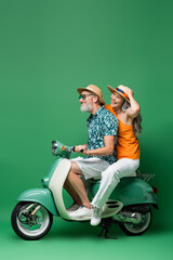 positive and interracial middle aged couple in sun hats riding motor scooter on green © LIGHTFIELD STUDIOS