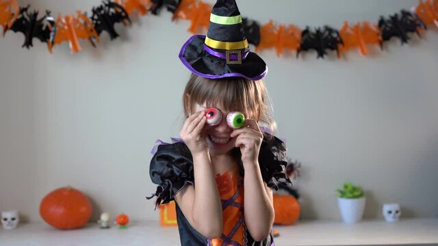 Little funny girl in witch costume playing home