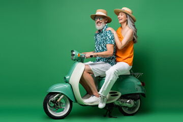 cheerful interracial middle aged couple in sun hats riding moped on green © LIGHTFIELD STUDIOS