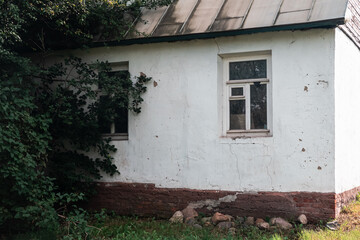 Fototapeta na wymiar Old whitewashed shabby country house. Russian national household. Smooth transition from positive light to dark and mysterious dark