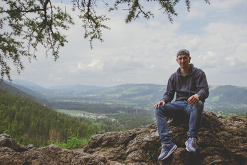 Male resting and enjoying the mountain sitting on rock