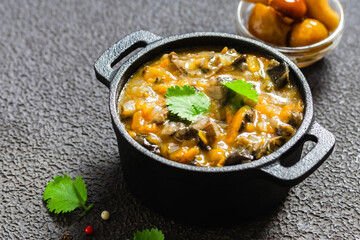 Vegan root vegetables mushroom stew in cast iron pot. Space for text.