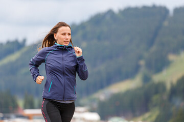 Young slim woman running on the road in the morning
