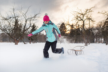 Fototapeta na wymiar Teengae girl having fun playing with the sledge in the snow in winter