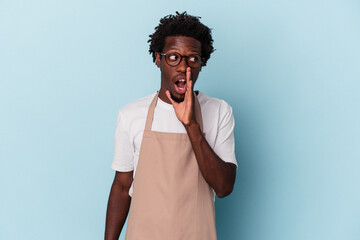 Young african american store clerk isolated on blue background is saying a secret hot braking news...