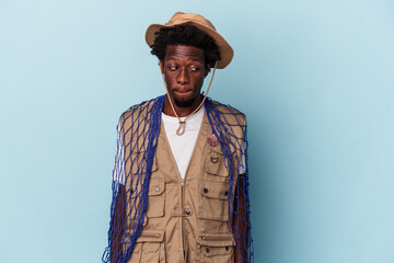 Young african american fisherman holding a net isolated on blue background confused, feels doubtful and unsure.